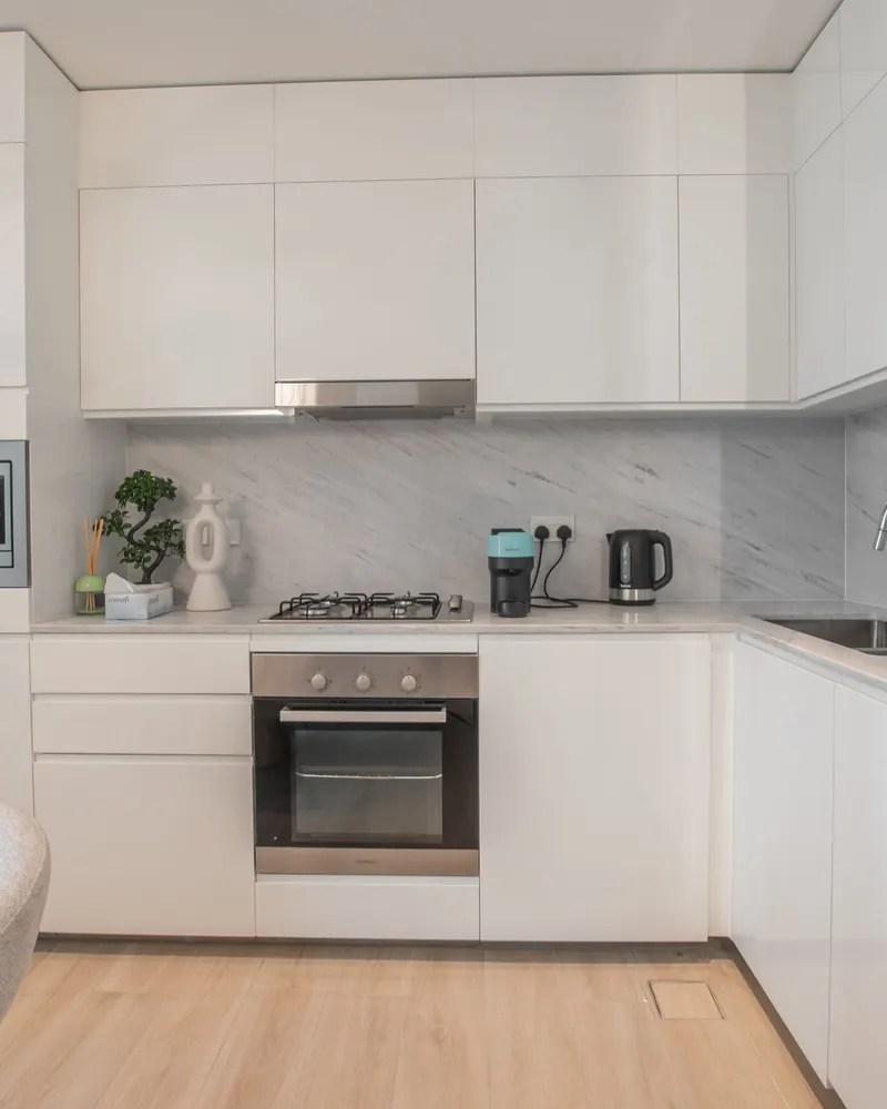A bright white kitchen with warm wood floors and clear countertops