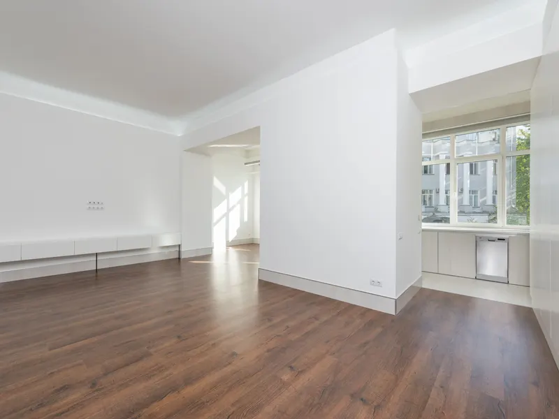 A bright empty apartment with wood floors, white walls and clear open rooms